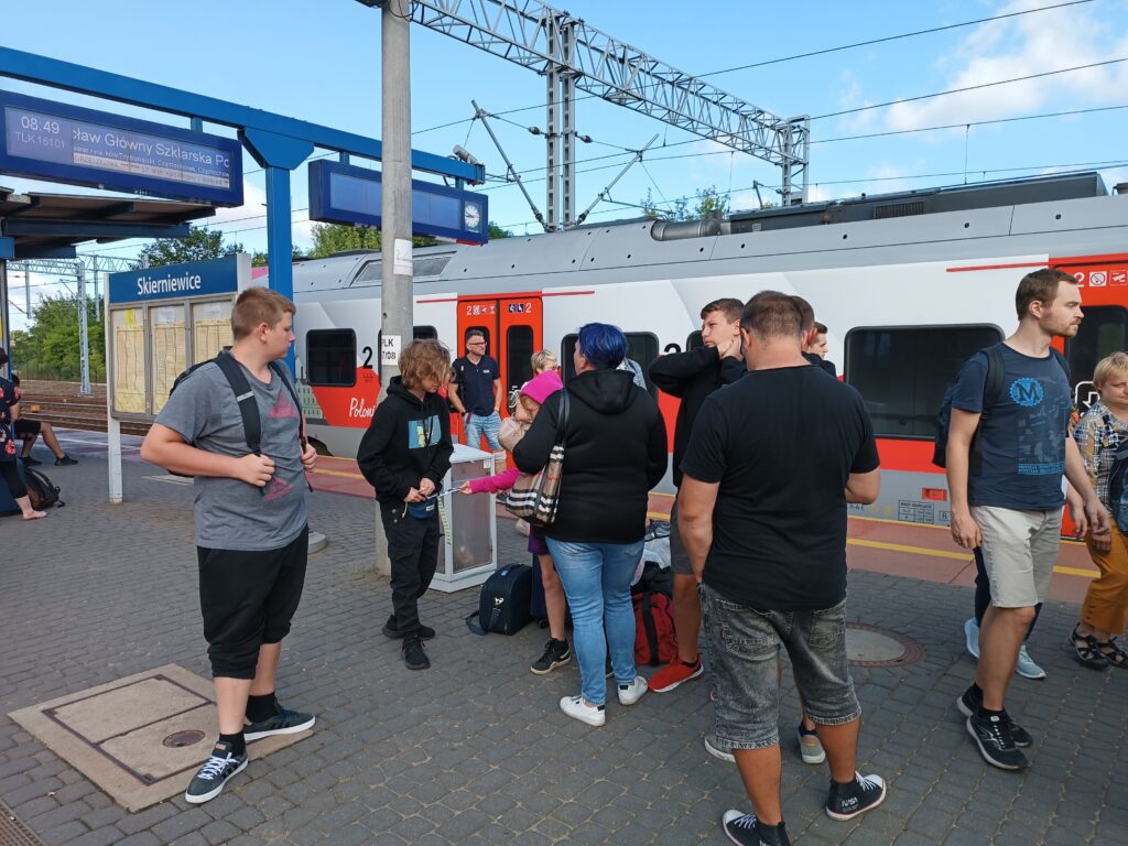 Liczna grupa uczestników wycieczki wysiada z pociągu