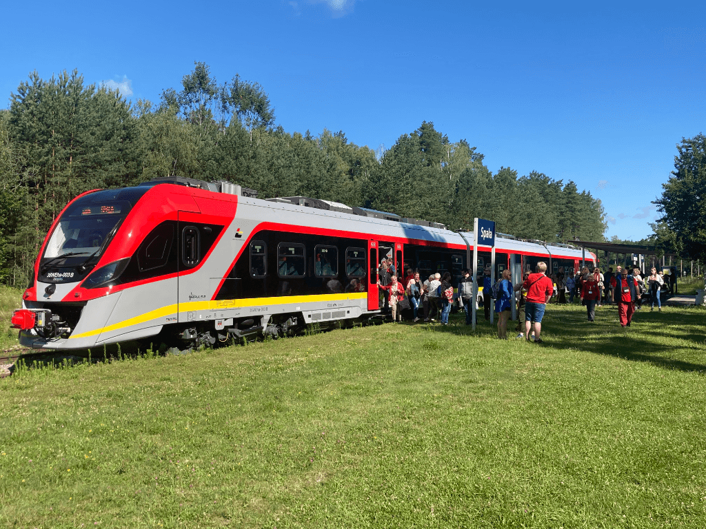 Uczestnicy wycieczki wysiadają z pociągu Łódzkiej Kolei Aglomeracyjnej na przystanku kolejowym w Spale.
